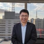 清华大学刘德华教授在巴西接受采访，背景为城市景观与中巴两国国旗