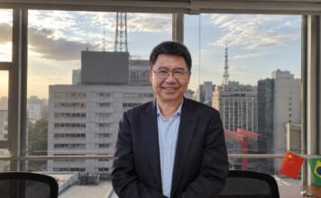 清华大学刘德华教授在巴西接受采访，背景为城市景观与中巴两国国旗